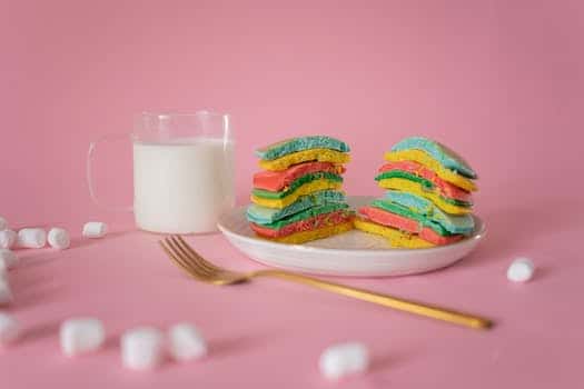 Delicious bright pancake served on plate near fork and white marshmallow on pink background