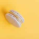 From above of delicious round shaped sweet macaroon placed on yellow background of studio