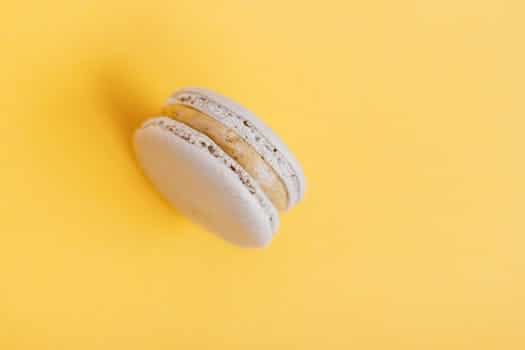 From above of delicious round shaped sweet macaroon placed on yellow background of studio