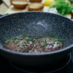 Frying pan with patties in kitchen