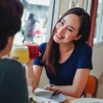 Happy Asian woman with drink in cafe