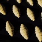 Top view composition of uncooked raw croissant dough arranged on surface of black glass in dark light