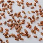 Top view of pile of delicious almond nuts cluttered on white table illustrating healthy food eating concept