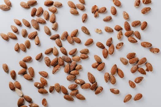 Top view of pile of delicious almond nuts cluttered on white table illustrating healthy food eating concept