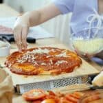 Woman sprinkling cheese on pizza