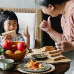 Crop woman with granddaughter having breakfast together