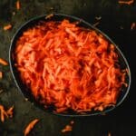 Heap of orange fresh grated carrot in baking pan