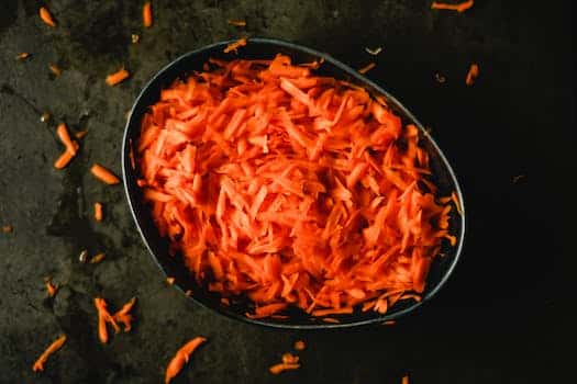 Heap of orange fresh grated carrot in baking pan